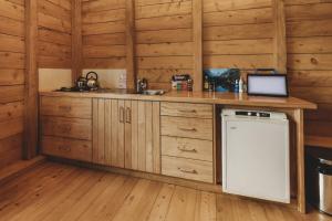 a kitchen with wooden cabinets and a sink and a dishwasher at The River Retreat - off the grid escape in Inglewood