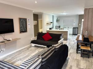 a living room with a black couch and a kitchen at Bliss at Diaz in Mossel Bay