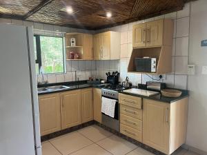 a kitchen with wooden cabinets and a stove top oven at Ufudu Chalet in Mbazwana