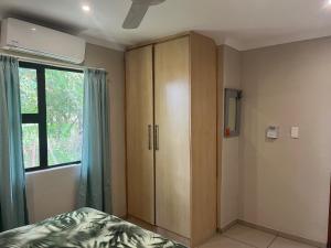 a bedroom with a bed and a cabinet and a window at Ufudu Chalet in Mbazwana
