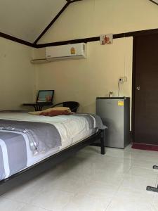 Un dormitorio con una cama y un frigorífico. en Mayow Bungalow Kohmook Trang, en Trang