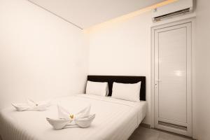 a white bed with two white flowers on it at Samara Stay by Sinergi in Kalibanteng-kidul