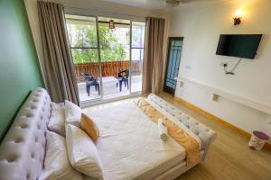 Una sala de estar con un sofá y una ventana grande. en Sands Garden Hotel, en Thoddoo