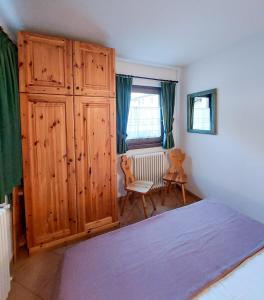 een slaapkamer met een grote houten kast en een bed bij Lo chalet di Lucky in Campodolcino +1 foto