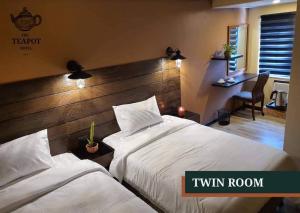 um quarto de hotel com duas camas e uma escrivaninha em The Teapot Hotel em Naga