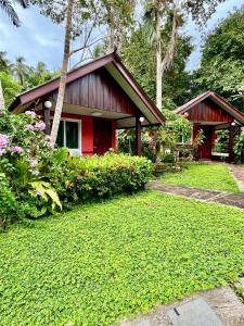 una casa roja con un césped verde delante de ella en Mayow Bungalow Kohmook Trang, en Trang