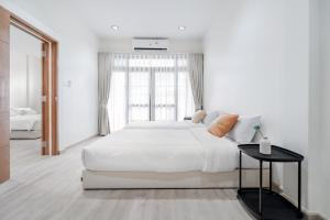 a white bedroom with a large bed and a window at Haus Ekkamai 2 in Khlong Toei