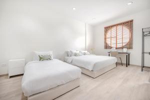 a white bedroom with two beds and a window at Haus Ekkamai 2 in Khlong Toei