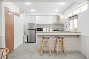 a kitchen with white appliances and two bar stools at Haus Ekkamai 2 in Khlong Toei