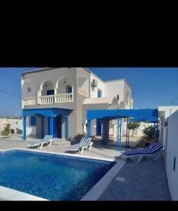 a large house with a swimming pool and chairs at Villa des deux frères in Midoun