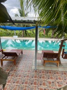 a swimming pool with two benches and a hammock at SriHOME in Ban Don Tum (1)