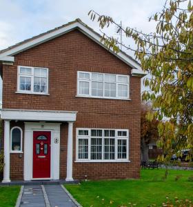 a red brick house with a red door at Smitten House 4 Bedroom RHYL in Rhyl