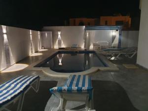 a swimming pool with two chairs and a bench at Villa des deux frères in Midoun