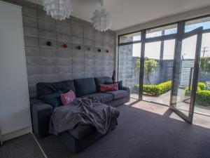 a living room with a blue couch and large windows at Fabulous In Fitzroy - seconds to Fitzroy Beach in New Plymouth
