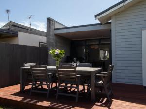 a table with chairs and a vase of flowers on a deck at Fabulous In Fitzroy - seconds to Fitzroy Beach in New Plymouth