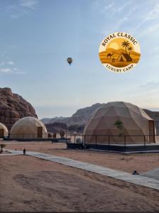 DisahRUM ROYAL CLASSIC lUXURY CAMP的一只风筝飞过沙漠中的两个圆顶。