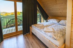 a bedroom with a bed and a balcony with a view at Widokowa Chata Istebna Trójwieś in Istebna +92 photos