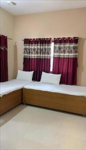 two beds in a room with red curtains at Dwarka Home Stay in Dwarka