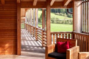a porch with a bench with a red pillow on it at Mountain Exzelent Residence - Luxury Alpine Apartments in Anterselva di Mezzo +67 photos