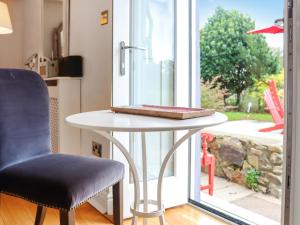 a table and a chair in front of a window at Snowdrop Cottage in Treffynnon 