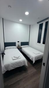 two beds in a room with two windows at bcool in Bilbao