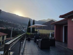 a patio with chairs and an umbrella on a balcony at Cottage Bela Vista by Escape to Madeira in Cedros