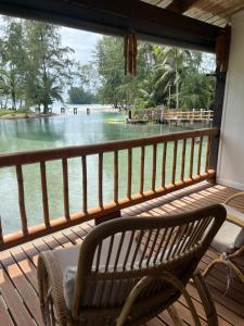 a bench sitting on a porch looking out at the water at À La Koh Kood Resort in Ko Kood