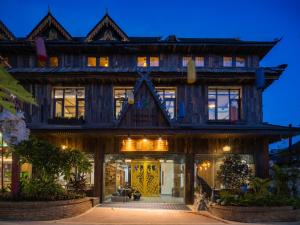 een groot houten gebouw met een voordeur 's nachts bij 22 Garden House in Jinghong