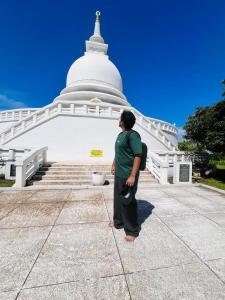 a man standing in front of a large white temple at Ocean breeze in Galle