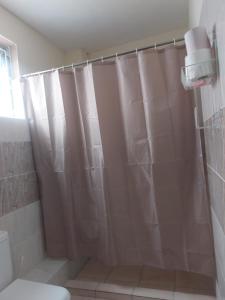 a bathroom with a shower curtain and a toilet at Pavilion Suites in Mombasa