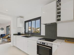 a kitchen with white cabinets and a stove top oven at 400m de la plage, jardin, maison pour 8 in Le Gillieux