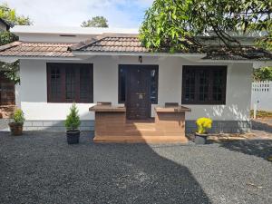 a white house with a brown door and stairs at Mount wave Pool villa in Wayanad