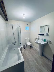 a bathroom with a tub and a sink and a toilet at Kirkgate Cottage - 2 Bedrooms - Sleeps 4 in Cockermouth