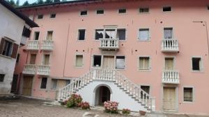 ein rosafarbenes Gebäude mit einer Treppe davor in der Unterkunft Appartamento Dolomiti Perarolo Tramonti sul Boite in Perarolo di Cadore