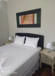 a bedroom with a large white bed and a nightstand at Hospedagem Altas da Quitéria Suíte 01 in Catas Altas +14 photos