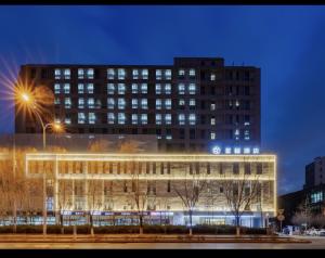 a large building with lights in front of it at Xingcheng Beijing Huilongguan Jishuitan Hospital Hotel in Beijing