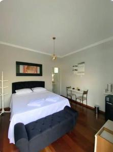 a bedroom with a large white bed and a table at Hospedagem Altas da Quitéria Suíte 01 in Catas Altas