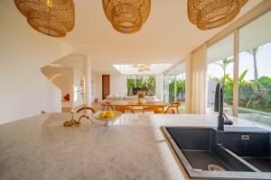 Il dispose d'une cuisine avec un évier et d'une salle à manger avec une table. dans l'établissement Luxury 3BR Seseh Villa Ocean View with Rooftop Lounge & Beach Access, à Cemagi