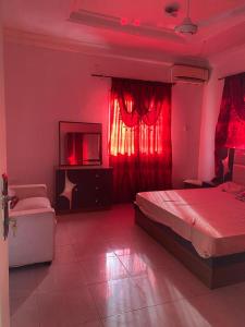 a bedroom with red lighting and a bed and a tv at Apartment Brusubi in Mbarra Kunku