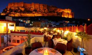 焦特布尔The Rajputana Haveli的餐厅配有桌椅,位于山脚下