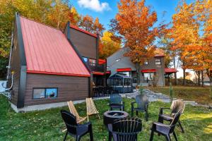 a house with a red roof and chairs in the yard at Spa & Nature view - Alpenglow in Sainte-Germaine-du-Lac-Etchemin