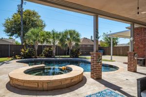 a pool in a patio with a brick fountain at King Suite House with Pool & BBQ in Rowlett