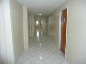 um corredor vazio com piso em azulejo branco e uma porta em Hotel Pio em Teresina