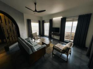 a living room with a couch and chairs and a tv at Coastline 4Bedroom cliffside villa in Elattūr