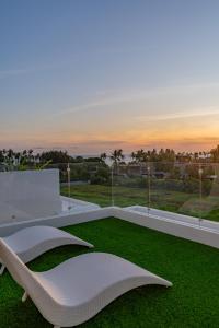 un canapé blanc sur un balcon donnant sur une pelouse verte dans l'établissement Luxury 3BR Seseh Villa Ocean View with Rooftop Lounge & Beach Access, à Cemagi