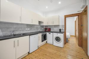 a kitchen with white cabinets and a washer and dryer at Studio 169 in London