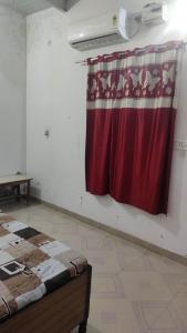 a bedroom with a red curtain on a wall at Yamuna Kunj Homestay in Govardhan +1 photo