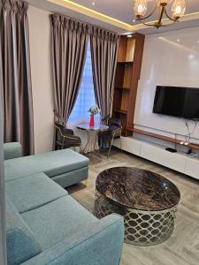 een woonkamer met een bank en een flatscreen-tv bij The 8 Luxury Apartments in Accra