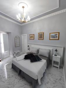 a white bedroom with a large bed and a chandelier at Le Nouveau Grand Tour - Dimora del Commendatore in San Giorgio Morgeto