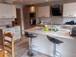a kitchen with a large white counter and stools at Smitten House 4 Bedroom RHYL in Rhyl +31 photos